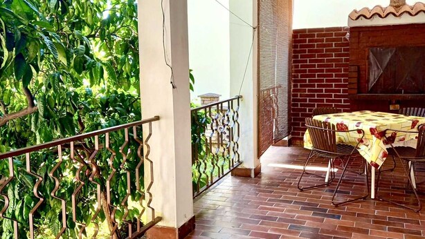 A covered outdoor area with a brick floor, a table with chairs, and a view of greenery. - Apartment Tea 2 close to the beach and city center (Umag)
