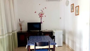 A dining area with a table, chairs, a TV, and a refrigerator. - Apartment Tea 2 close to the beach and city center (Umag)