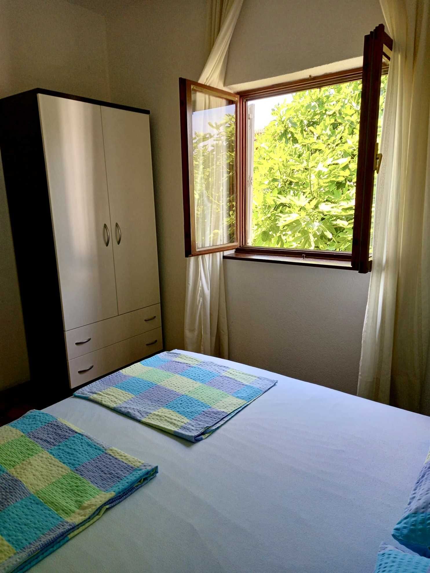 Ein Schlafzimmer mit Bett, Kleiderschrank und einem Fenster mit Vorhängen.