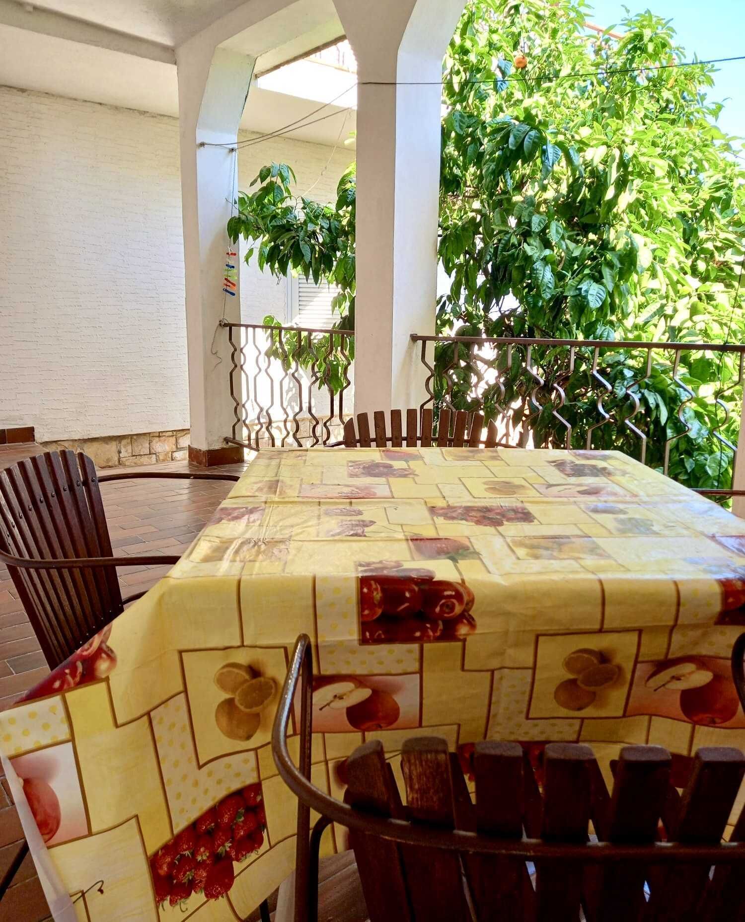 Un espace extérieur abrité, aménagé pour les repas, avec une table pour deux, entourée de chaises, et offrant une vue sur une végétation luxuriante.