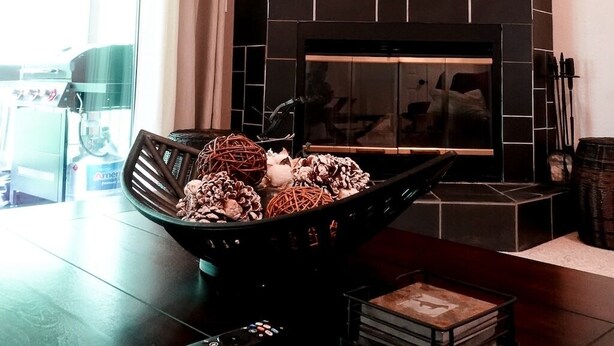A modern living room with a fireplace, a black-framed mirror, and a bowl of decorative items on a wooden table. - Stylish 2 BR & 2 bath + Loft Durango Condo near Purgatory (Durango)