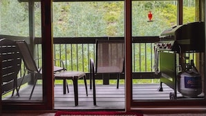 A covered outdoor area with a grill, chairs, and a view of a forested area. - Stylish 2 BR & 2 bath + Loft Durango Condo near Purgatory (Durango)