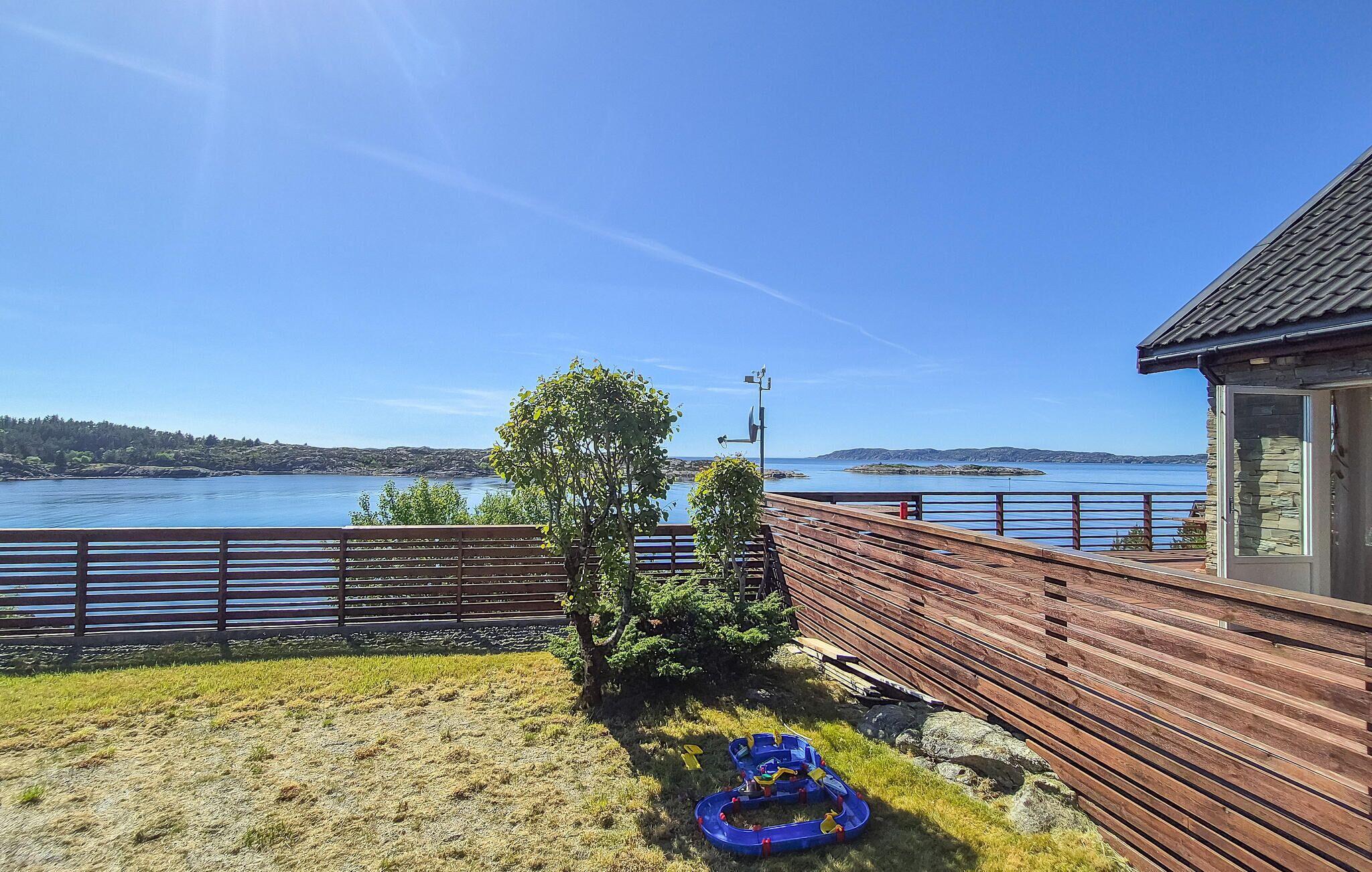 Una terraza de madera con vistas a un lago, donde se aprecia claramente el agua y unas islas a lo lejos.