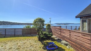 A wooden deck overlooking a lake with a clear view of the water and distant islands. - Cozy home in Sveio with WiFi (Sveio)