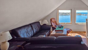 A cozy living room with a dark leather sofa, a wooden coffee table, and a pool table. There are two windows offering a view of the sea. - Cozy home in Sveio with WiFi (Sveio)