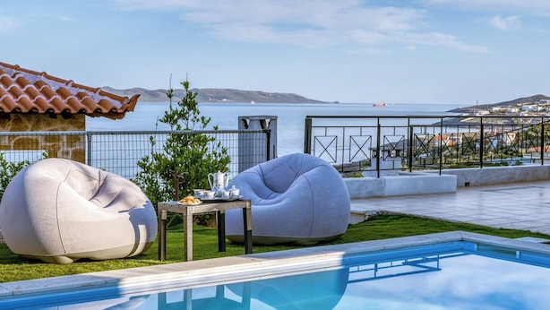 Ein Poolbereich mit Meerblick, ein Ziegeldach sowie ein Tisch mit Teekanne und Tassen.