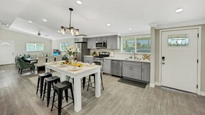A modern kitchen with a central island, stainless steel appliances, and a dining area with bar stools. - BOOK NOW!!! Your vacation awaits your home for Disneyland and OC destinations. (Anaheim)