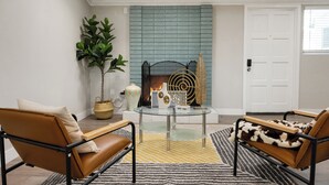 A living room with a fireplace, two leather chairs, a glass coffee table, and a patterned rug. - BOOK NOW!!! Your vacation awaits your home for Disneyland and OC destinations. (Anaheim)