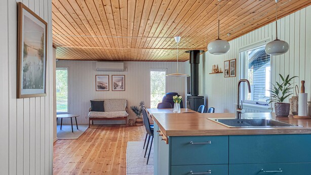 A cozy interior with a wooden ceiling, a dining area, a kitchen with a sink, and a teal cabinet. - Gorgeous home in Læsø with WiFi (Læsø)