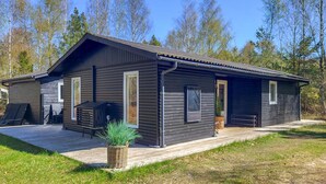 A modern log cabin with a covered patio, a grill, and a small garden area. - Gorgeous home in Læsø with WiFi (Læsø)