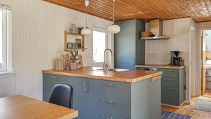 A kitchen with a wooden countertop, a sink, and a stove. There is a dining table and a chair. - Gorgeous home in Læsø with WiFi (Læsø)