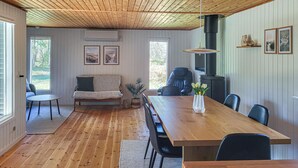 A cozy room with a wooden ceiling, a sofa, a dining table with chairs, and a fireplace. - Gorgeous home in Læsø with WiFi (Læsø)