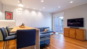 A modern living room with a dining area, a sofa, a TV, and a wooden cabinet.