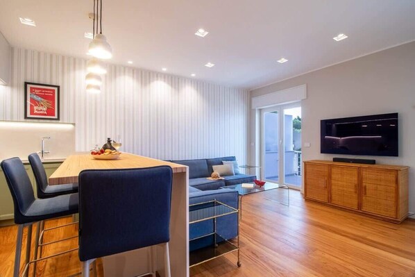 Una sala de estar moderna con comedor, un sofá, un televisor y un mueble de madera.