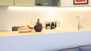 A kitchen with a white countertop, a bowl of food, a wine glass, and a coffee machine.