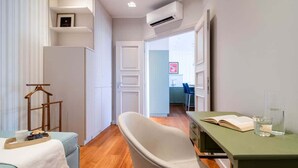 A compact living space with a sofa, a chair, a small table, and a kitchenette area.
