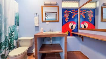 A bathroom with a toilet, sink, and mirror. There is a towel rack and a window with curtains.