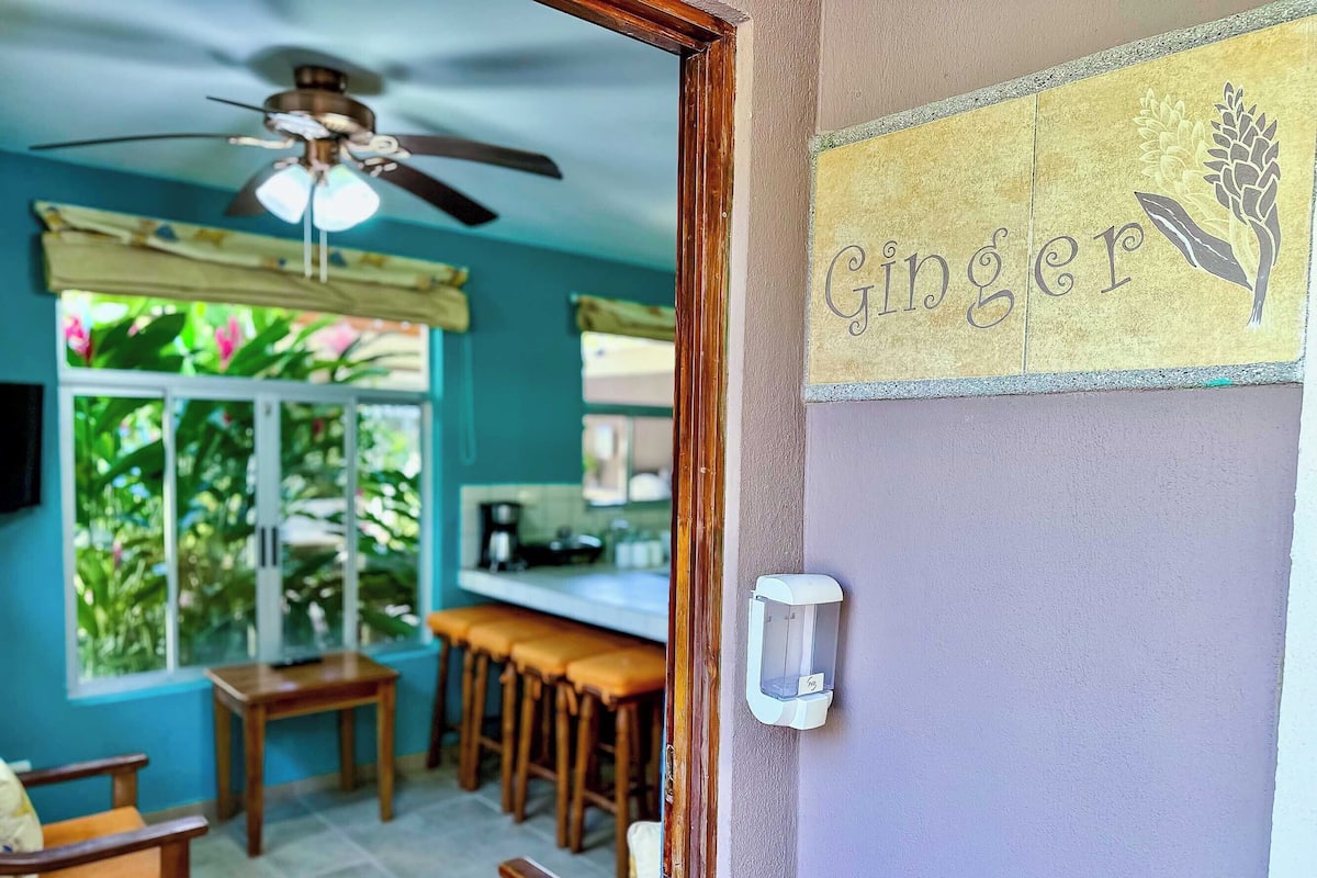 A kitchen with a ceiling fan, a window with curtains, and a bar area with stools.