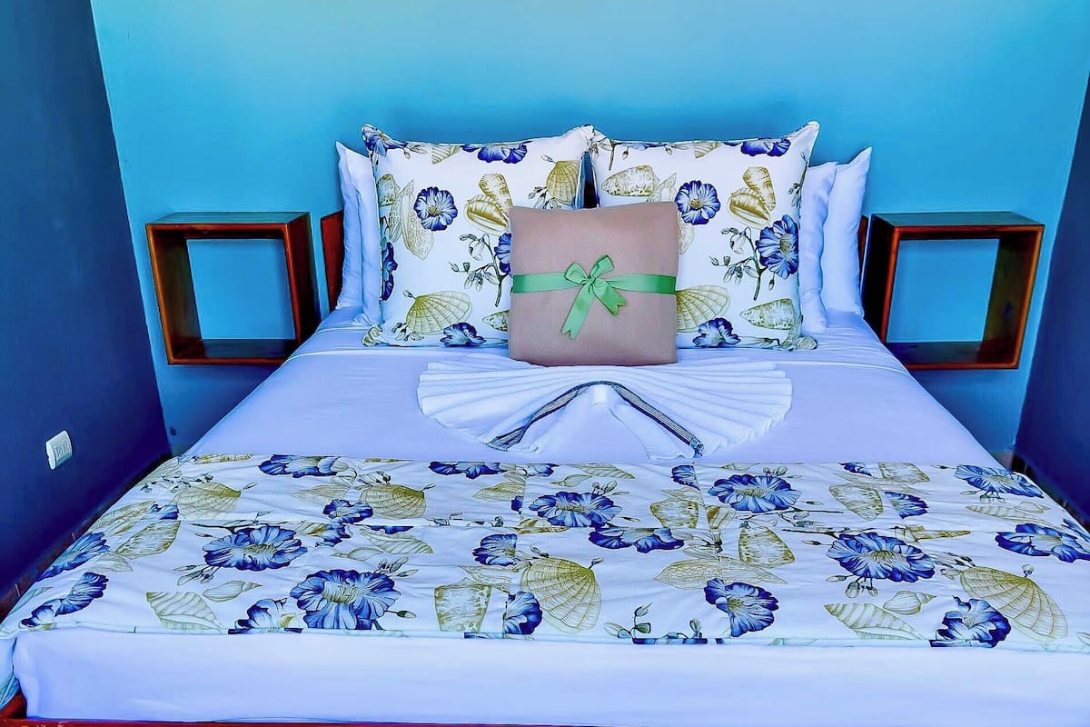 A bed with floral bedding, a decorative pillow, and wooden headboards.