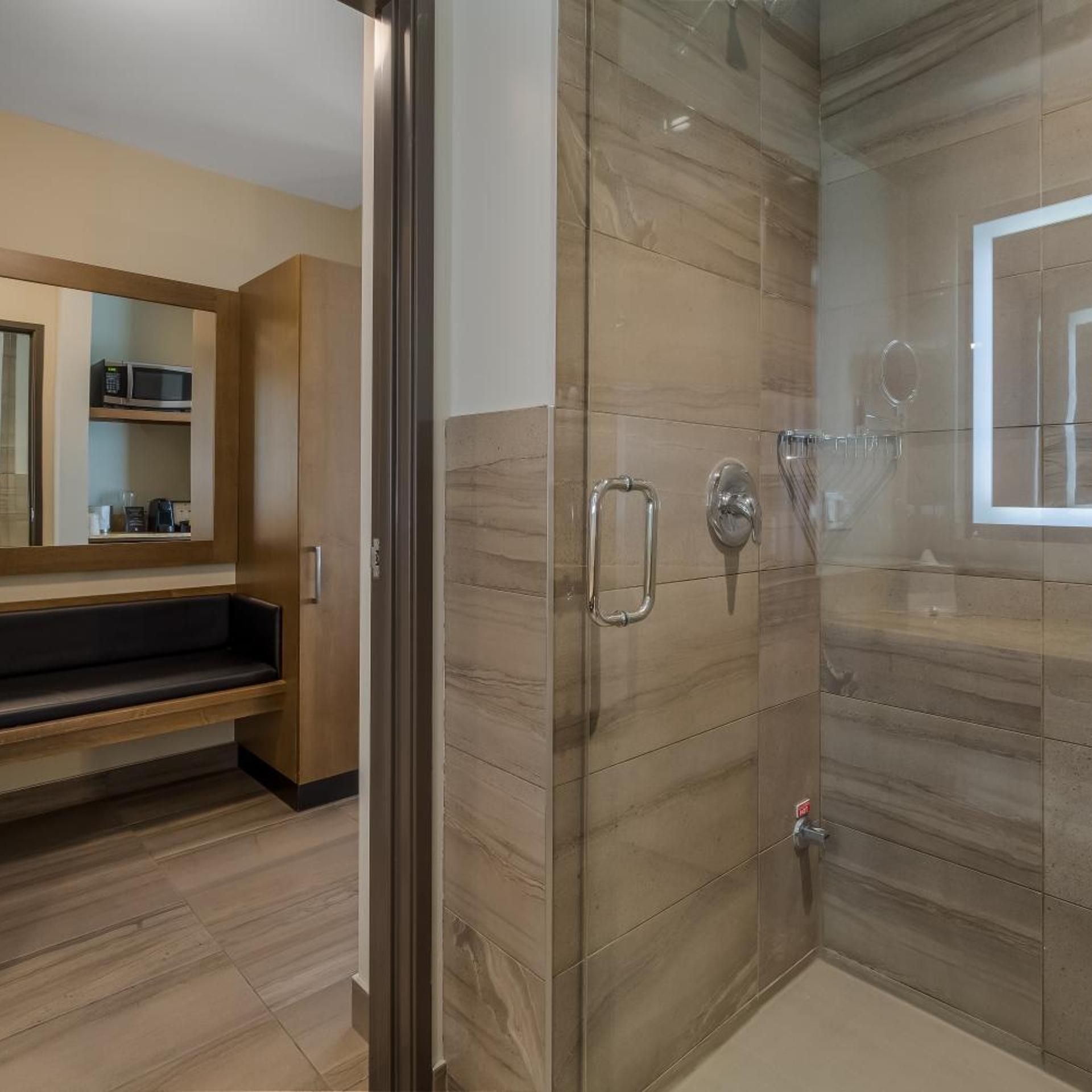 Une salle de bain moderne avec une douche à parois de verre, un meuble-lavabo avec un miroir et un banc en bois.