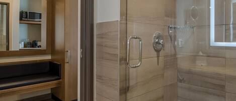 Une salle de bain moderne avec une douche à parois de verre, un meuble-lavabo avec un miroir et un banc en bois.