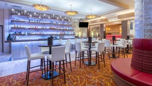 Zona de bar con diversas opciones de asientos, una barra bien iluminada y una pantalla de televisión.