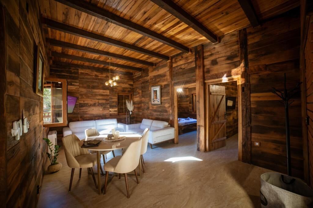 A rustic wooden interior with a dining area, white sofa, and a cozy ambiance.