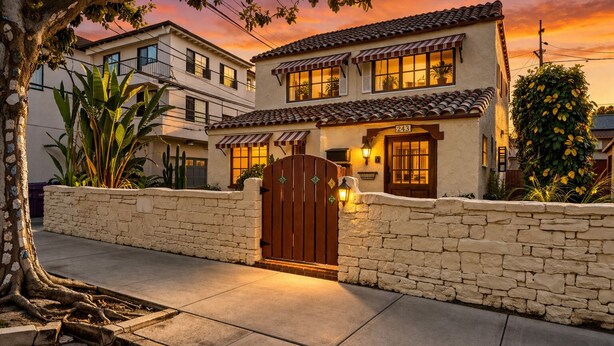 A two-story house with a stone wall, a wooden gate, and a number '243' on the front.
