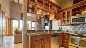 A spacious kitchen with wooden cabinets, a built-in stove, and a microwave. - Marazul Belize (Placencia)