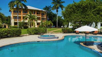 Una piscina al aire libre, sombrillas, sillones reclinables de piscina