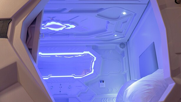 A futuristic interior with geometric patterns and illuminated blue lines on the walls.