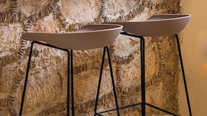Two metal bar stools with a stone wall background.