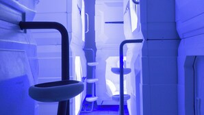 A narrow corridor with bunk beds and a small table, suggesting a dormitory or hostel setting.