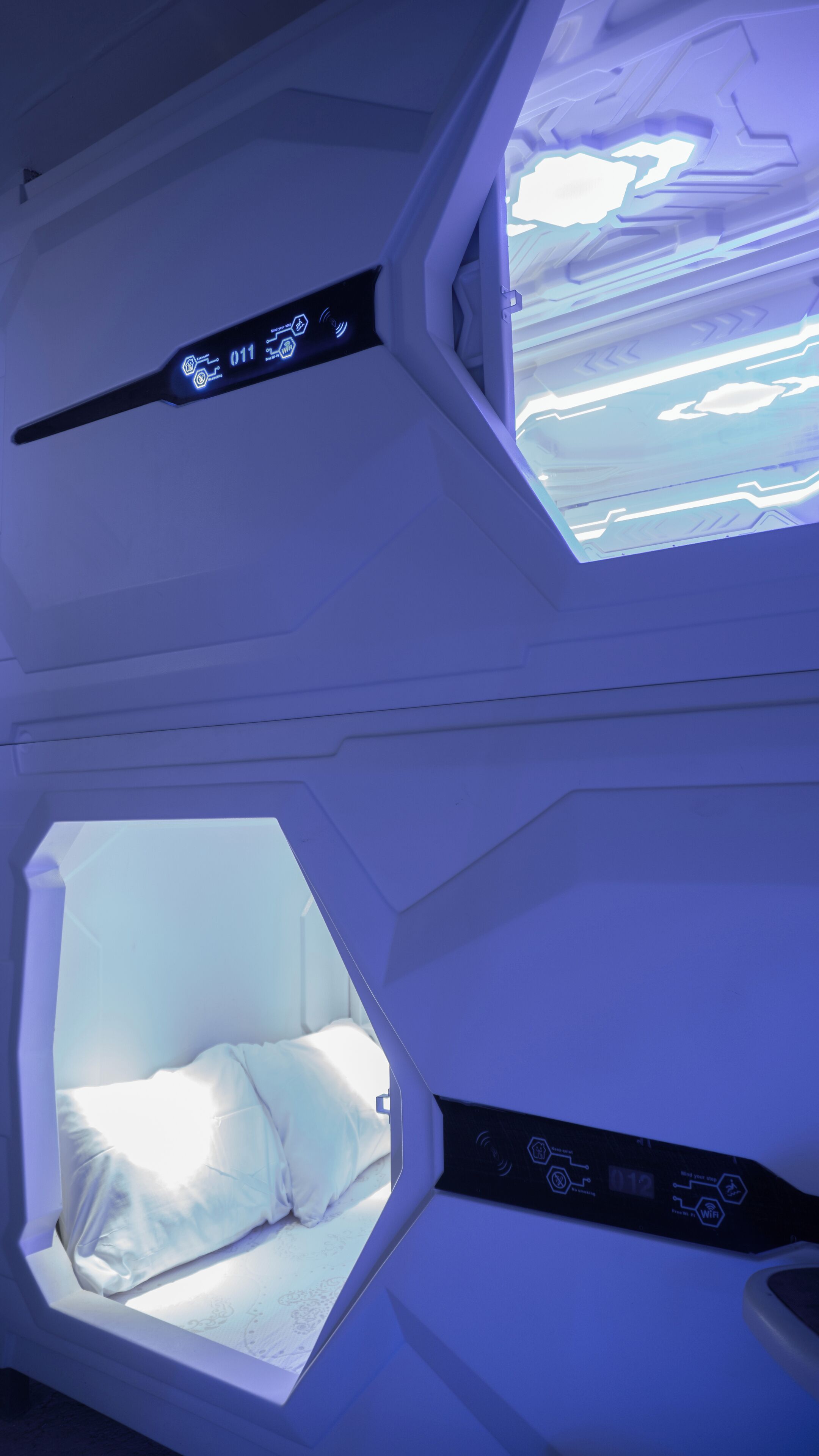 A room with a bed, a control panel, and a window with a view of the sky.