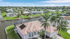 A waterfront property with a large house featuring a covered patio, a swimming pool, and a boat dock.