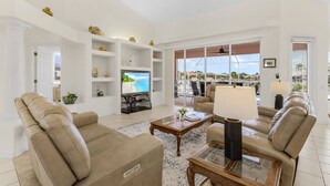 A spacious living room with a large TV, comfortable seating, and a view of the outdoors.