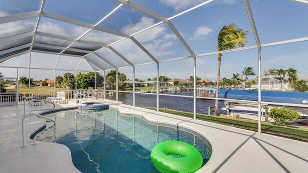 A covered swimming pool with a view of a marina and palm trees.