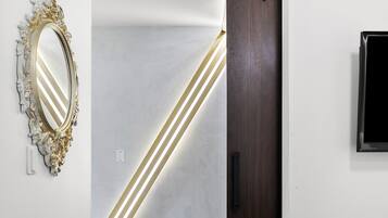 A modern interior with a wooden floor, a dark wooden door, a white wall, and a decorative mirror.