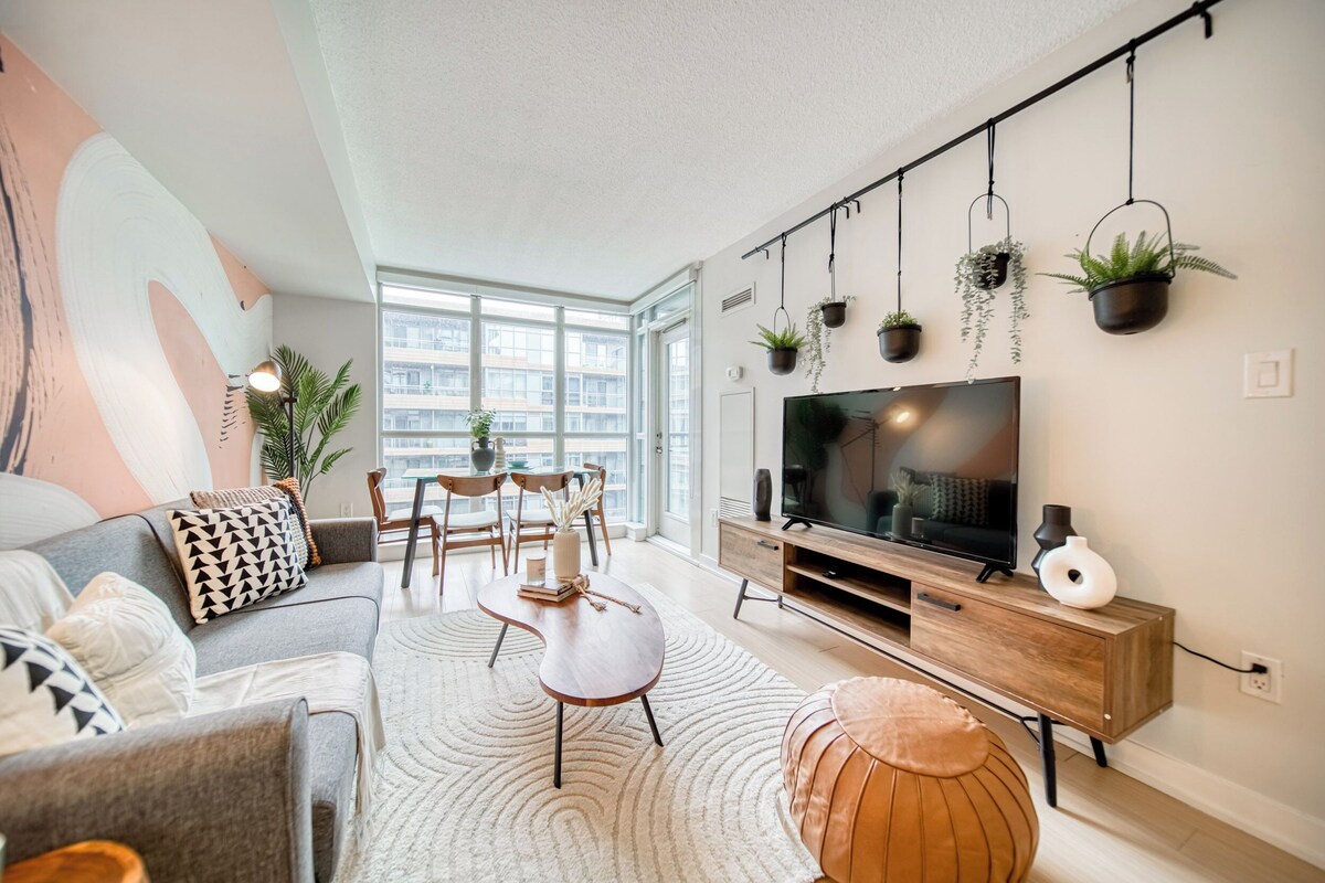 Uma sala de estar moderna com sofá, mesa de centro, televisão e plantas penduradas.