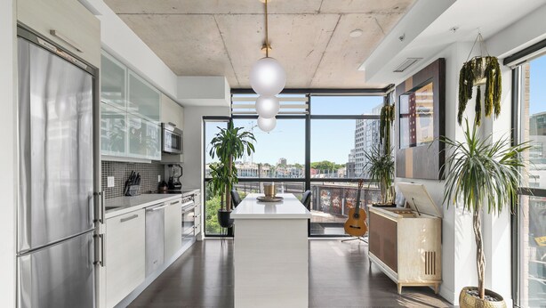 A modern kitchen with a central island, stainless steel appliances, and large windows offering city views. - Ohio Global Stay (Toronto)