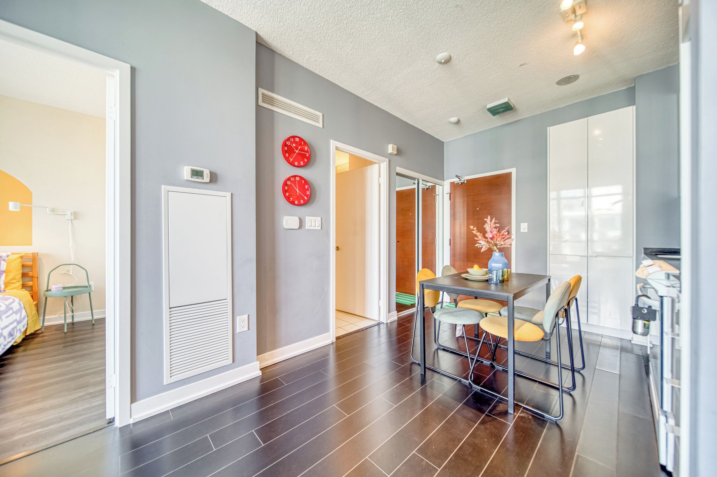 A modern apartment with a dining area, kitchenette, and a bedroom.