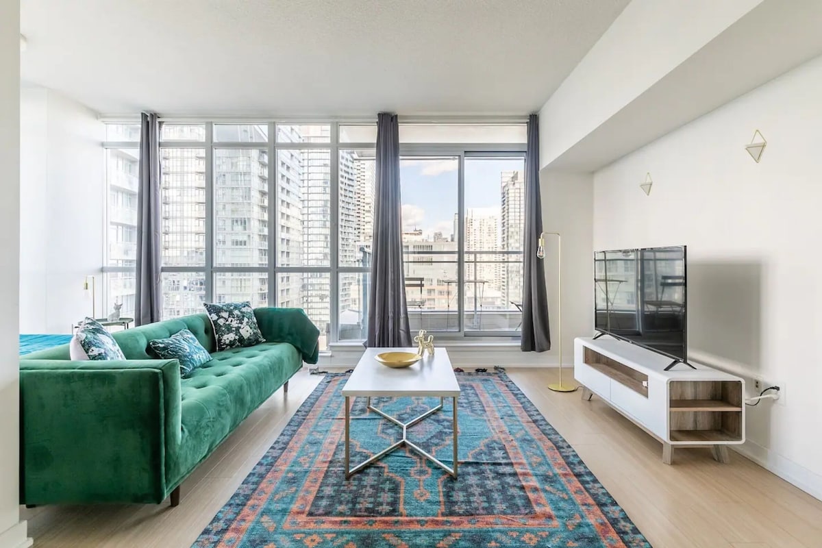 Uma sala de estar moderna com um sofá verde, uma mesa de centro branca e uma TV sobre um suporte branco.