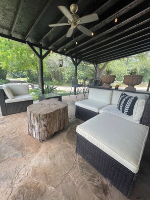 An outdoor patio with wicker furniture, a ceiling fan, and potted plants. - SPACE COWBOY cabin/studio (Whitney)