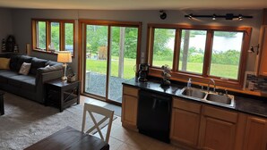 A modern kitchen with a dishwasher, sink, and large windows offering a view of a lake.
