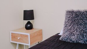A bedroom with a bed, a nightstand with a lamp, and a pillow. - Single Room With Shared Bathroom (Capertee)
