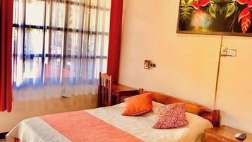 Familjerum - utsikt mot trädgården | Värdeförvaringsskåp på rummet, skrivbord och arbetsyta för laptop