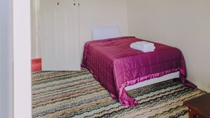 Une pièce avec un lit, une porte et un tapis à rayures.