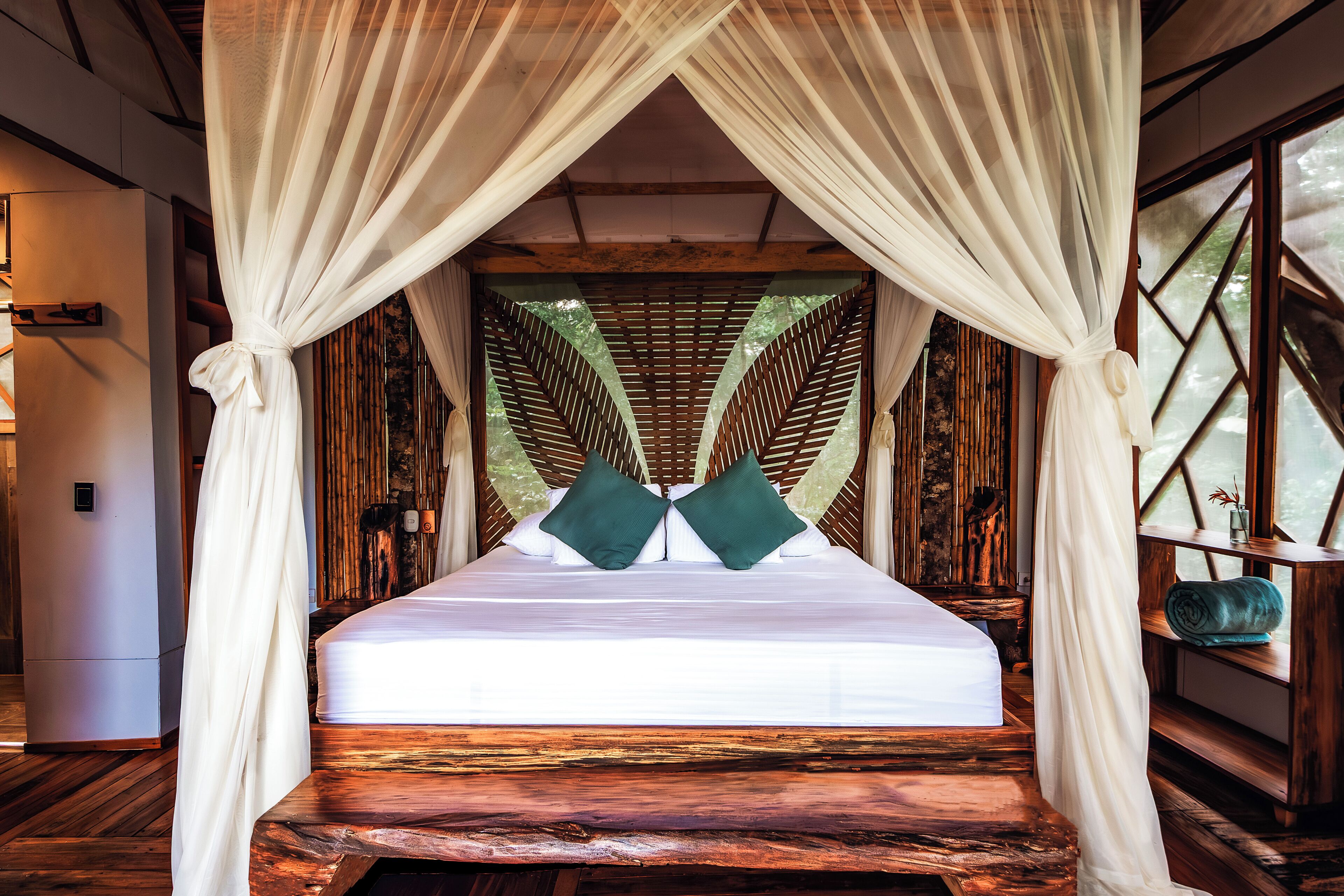 A bed with a canopy, wooden flooring, and a view through the canopy.