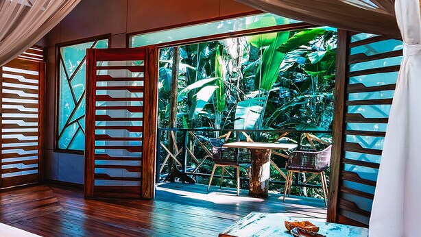 Une pièce spacieuse avec un grand lit, une table en bois et une vue sur un paysage verdoyant.