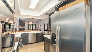 Una cocina moderna con refrigerador de acero inoxidable, gabinetes negros y encimera de madera.